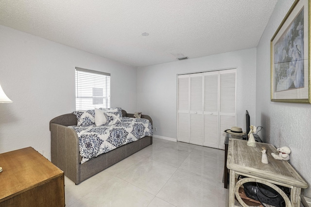 tiled bedroom featuring a textured ceiling and a closet