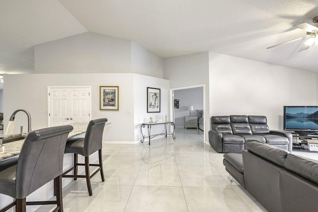 living room featuring ceiling fan, sink, a textured ceiling, and lofted ceiling