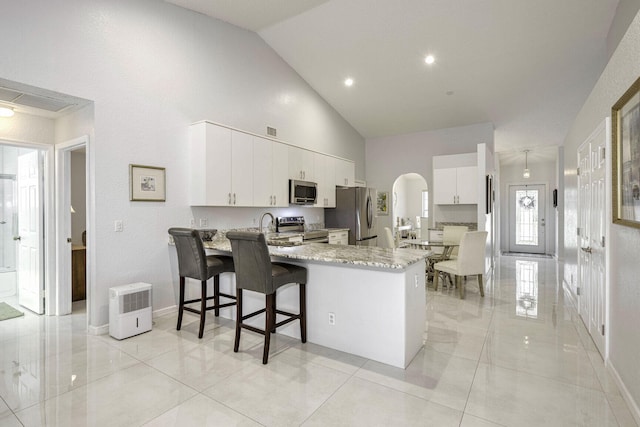 kitchen with kitchen peninsula, white cabinets, a kitchen breakfast bar, and appliances with stainless steel finishes