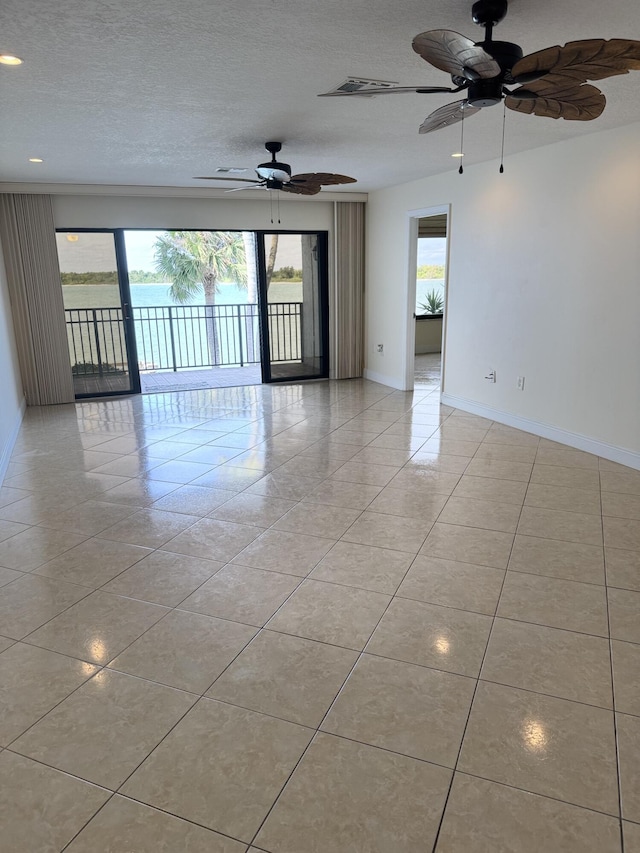 tiled spare room featuring a textured ceiling, plenty of natural light, and ceiling fan