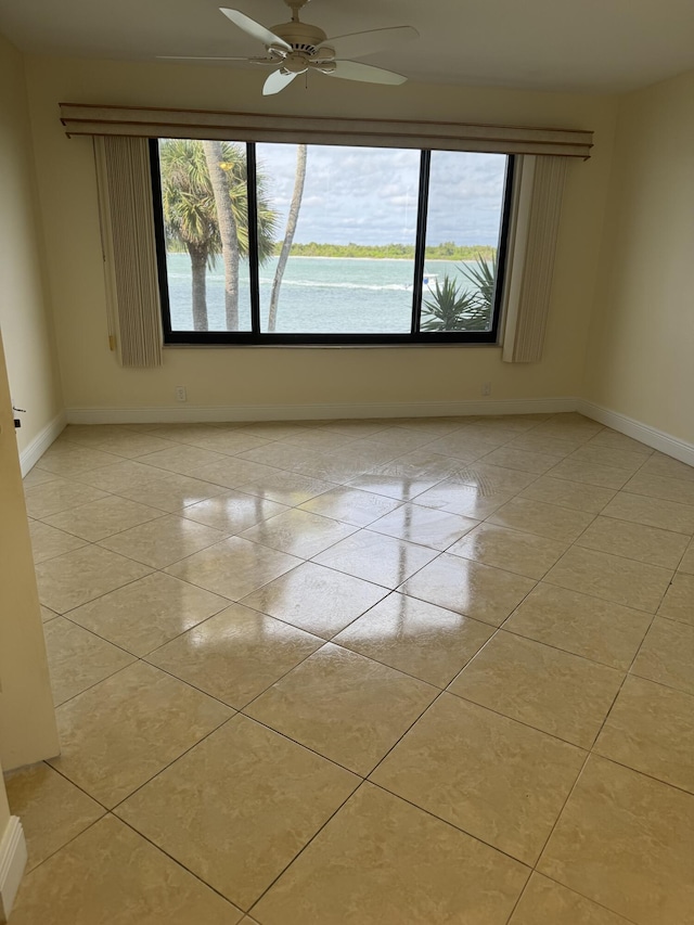 spare room with a water view, ceiling fan, and light tile patterned flooring