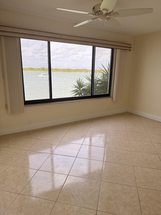 empty room with a water view, plenty of natural light, and light tile patterned floors