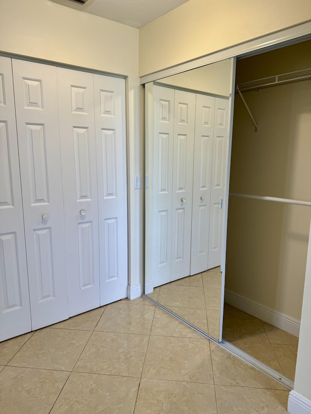 unfurnished bedroom with multiple closets and light tile patterned floors