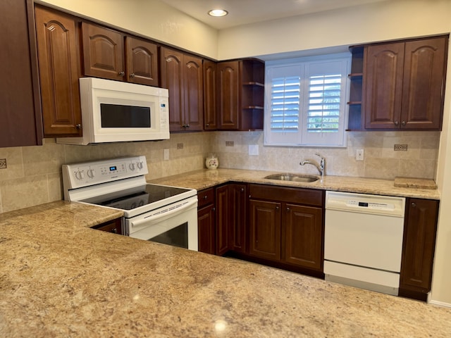 kitchen featuring sink, light stone counters, backsplash, and white appliances