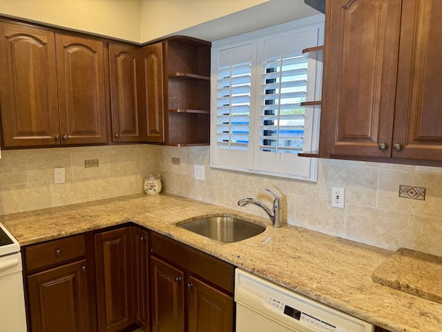 kitchen with light stone counters, dishwasher, sink, and backsplash