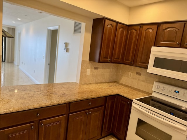 kitchen with tasteful backsplash, white appliances, and light stone countertops