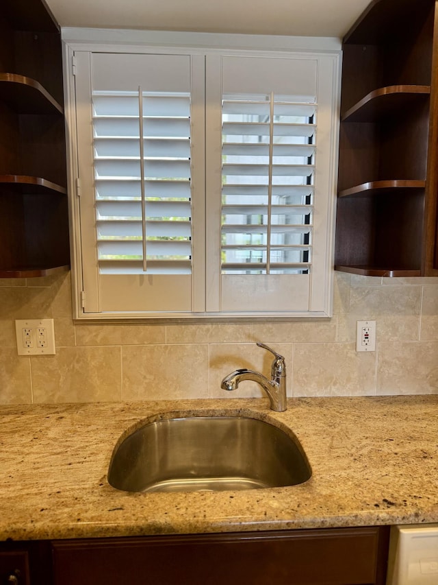 kitchen with sink, light stone counters, and decorative backsplash