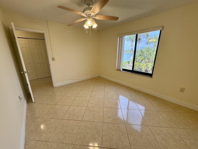 tiled empty room featuring ceiling fan