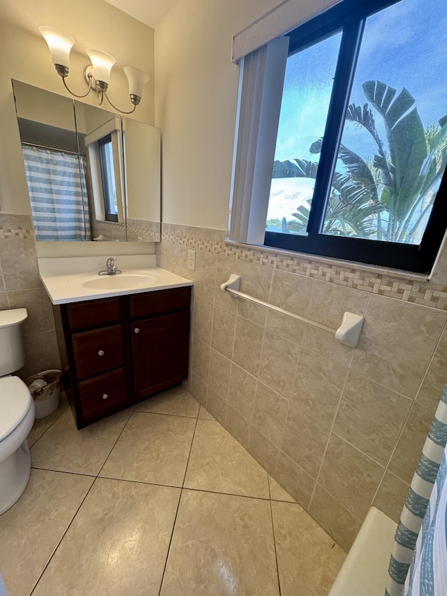 bathroom featuring tile walls, vanity, curtained shower, tile patterned floors, and toilet