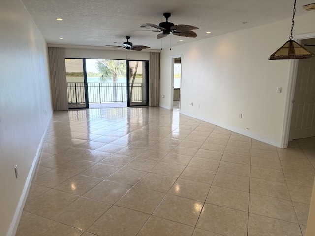 tiled empty room with ceiling fan and a textured ceiling