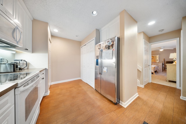 kitchen with white cabinetry, light hardwood / wood-style flooring, and white appliances