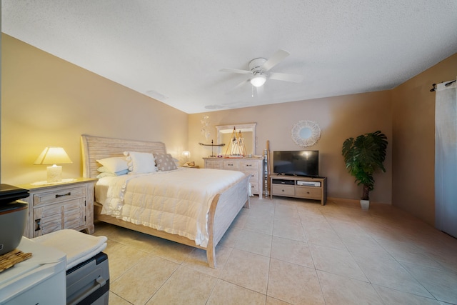 bedroom featuring ceiling fan, light tile patterned floors, and a textured ceiling