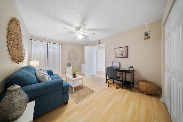 living room featuring ceiling fan, a textured ceiling, and hardwood / wood-style flooring