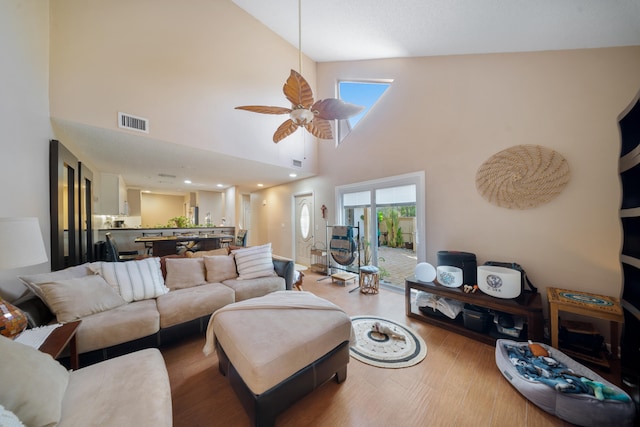 living room with ceiling fan, hardwood / wood-style floors, and a high ceiling