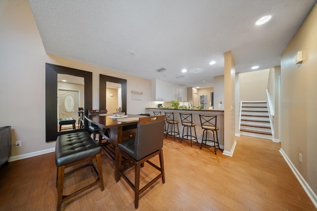 dining room featuring a textured ceiling and light hardwood / wood-style flooring