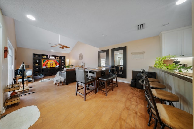 dining room with a textured ceiling, ceiling fan, lofted ceiling, and light hardwood / wood-style flooring