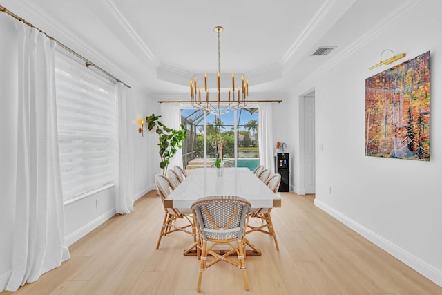 dining area featuring crown molding, a tray ceiling, and light hardwood / wood-style floors