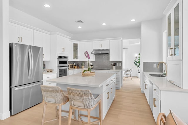 kitchen featuring a kitchen island, sink, a breakfast bar area, white cabinets, and stainless steel appliances