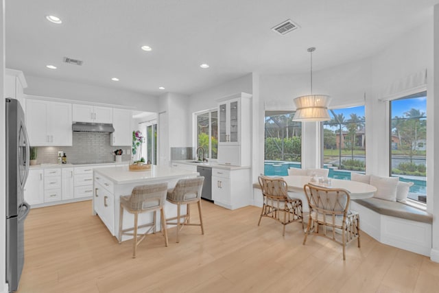 kitchen featuring white cabinetry, hanging light fixtures, and stainless steel appliances