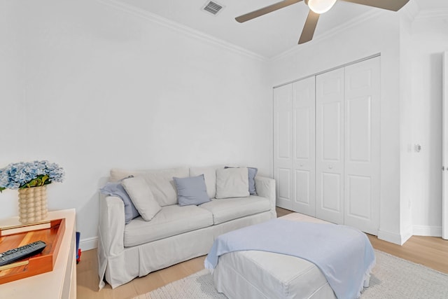 living room with crown molding, ceiling fan, and light wood-type flooring