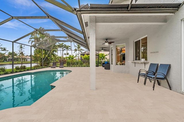 view of pool featuring a water view, a patio, ceiling fan, and glass enclosure