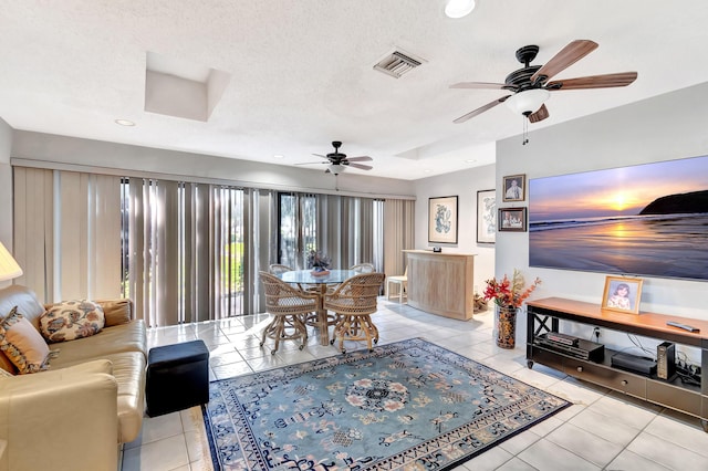 tiled living room with ceiling fan and a textured ceiling