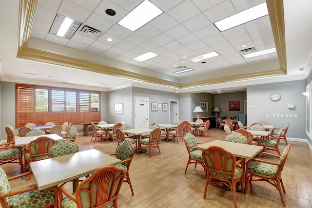 dining space with crown molding, a tray ceiling, and light hardwood / wood-style floors