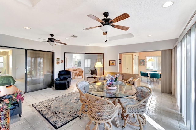 dining space with ceiling fan, a textured ceiling, and light tile patterned flooring