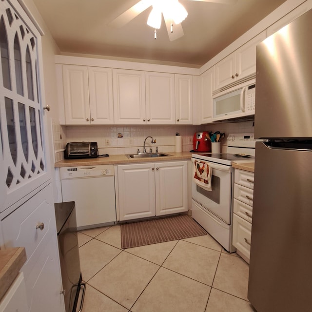 kitchen with sink, white appliances, light tile patterned floors, backsplash, and white cabinets