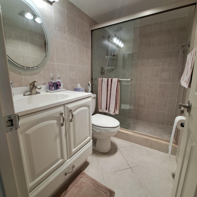 bathroom with tile patterned floors, vanity, tile walls, toilet, and a shower with shower door