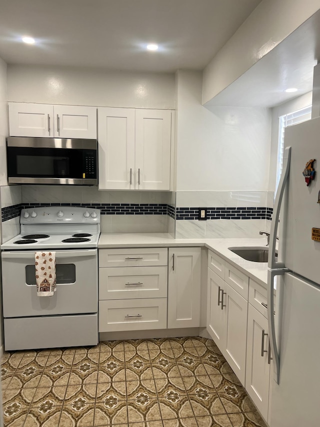 kitchen with light tile patterned floors, sink, white cabinets, and white appliances