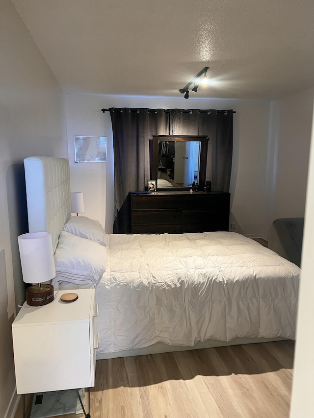 bedroom featuring a textured ceiling and light hardwood / wood-style floors