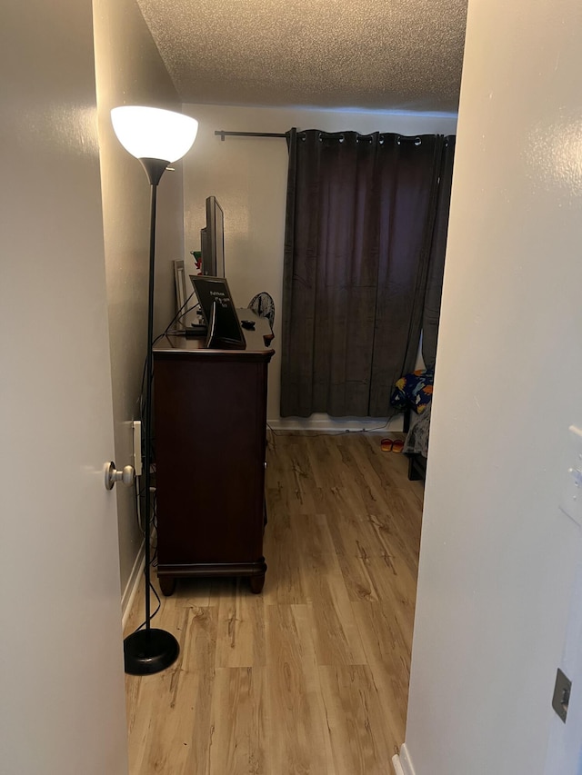 corridor featuring a textured ceiling and light hardwood / wood-style flooring