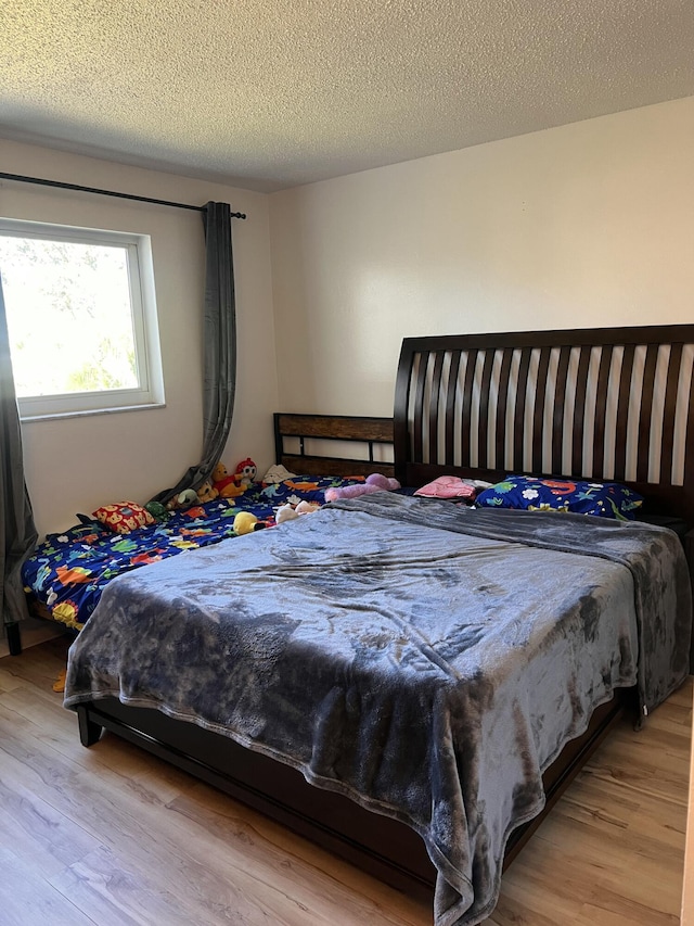 bedroom with a textured ceiling and light hardwood / wood-style floors