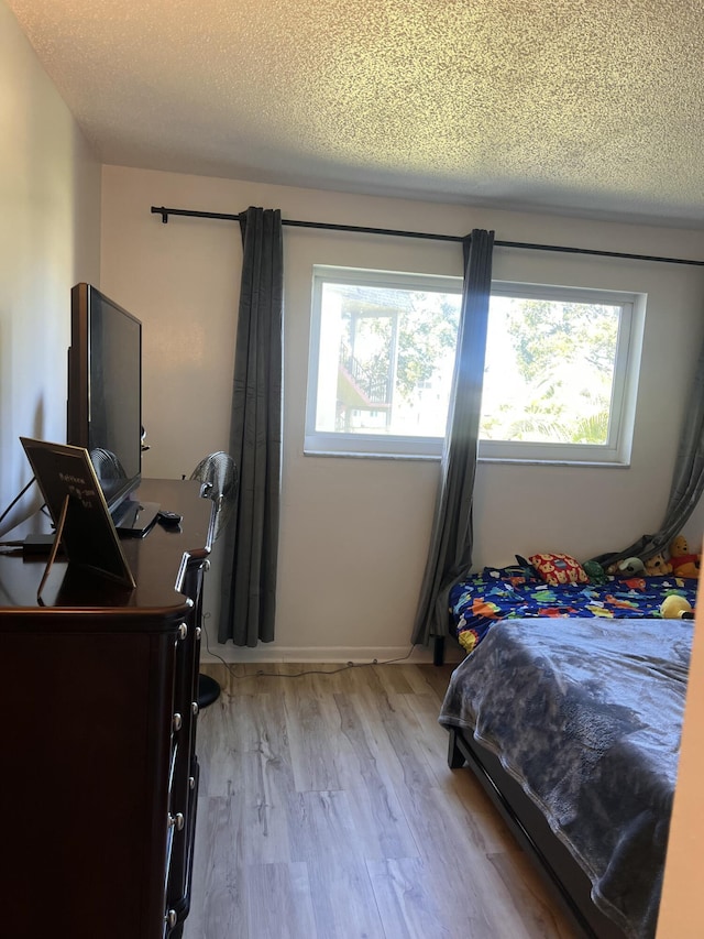 bedroom featuring light wood-type flooring and a textured ceiling