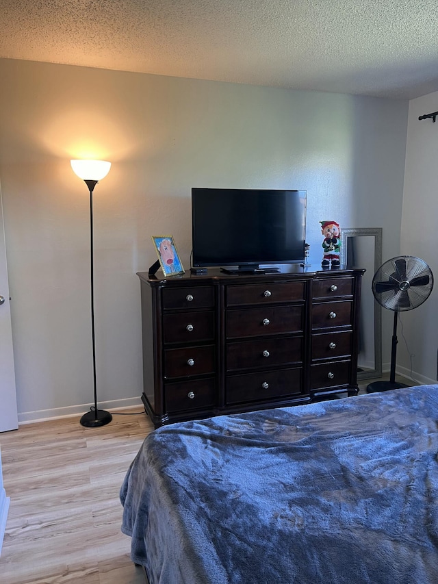 bedroom with a textured ceiling and light hardwood / wood-style floors