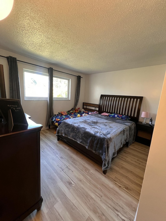 bedroom featuring a textured ceiling and light hardwood / wood-style flooring