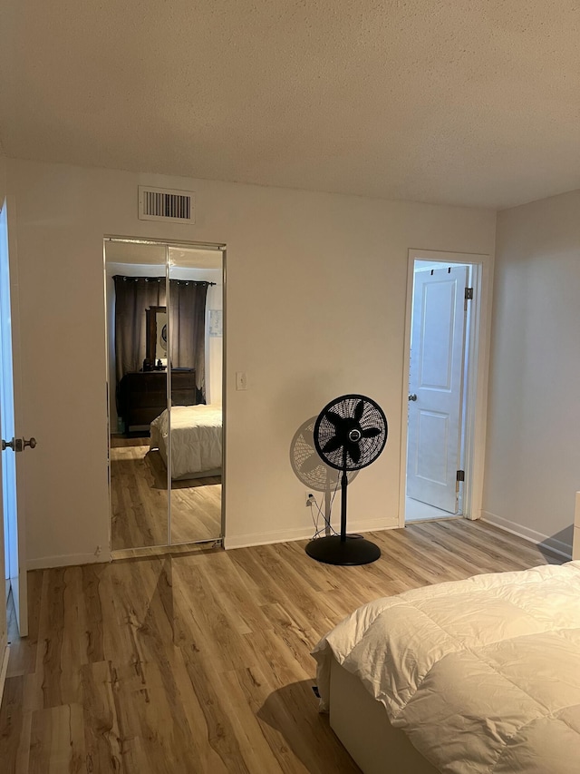 bedroom featuring wood-type flooring, a textured ceiling, and a closet