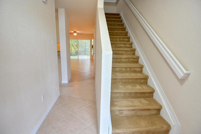 stairs with ceiling fan and tile patterned floors