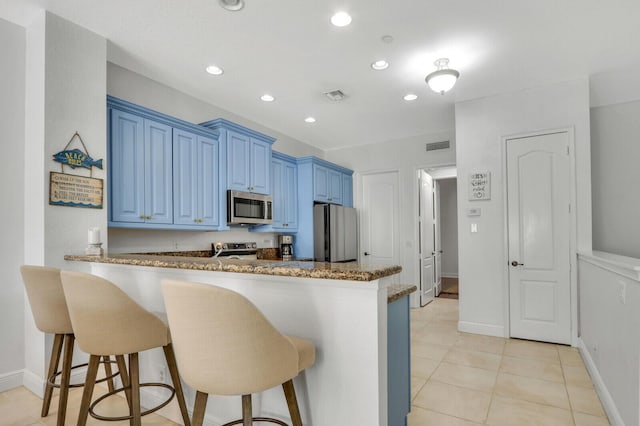 kitchen featuring blue cabinetry, light tile patterned floors, a kitchen breakfast bar, kitchen peninsula, and stainless steel appliances