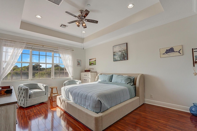 bedroom with ceiling fan, a tray ceiling, and dark hardwood / wood-style flooring