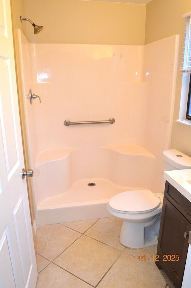 bathroom with tile patterned floors, toilet, vanity, and walk in shower