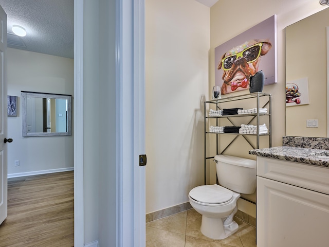 bathroom featuring toilet, vanity, tile patterned flooring, and a textured ceiling