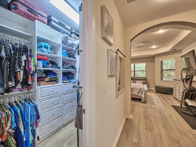 walk in closet featuring a raised ceiling and light hardwood / wood-style flooring