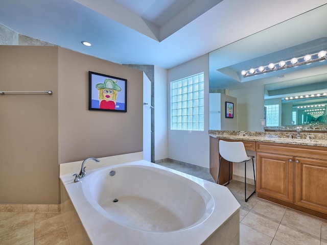 bathroom with a relaxing tiled tub, vanity, a raised ceiling, and tile patterned flooring