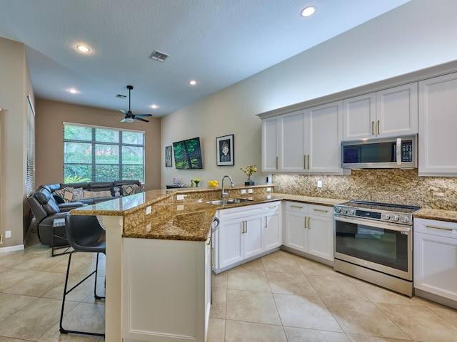 kitchen with kitchen peninsula, sink, dark stone countertops, and stainless steel appliances