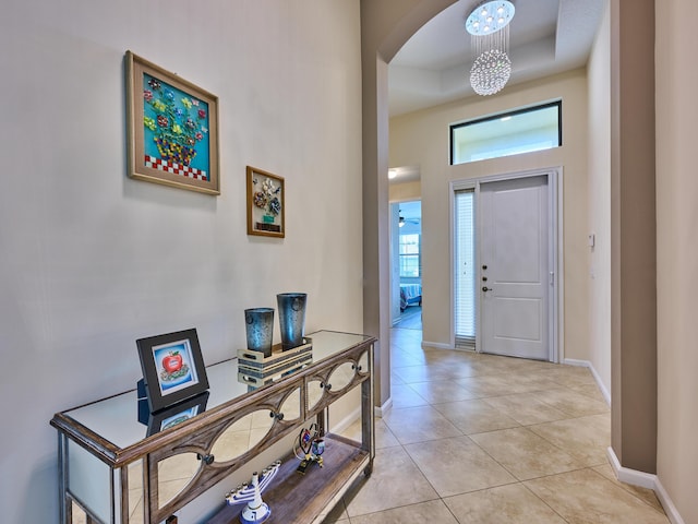 entrance foyer featuring light tile patterned floors, a towering ceiling, and a tray ceiling