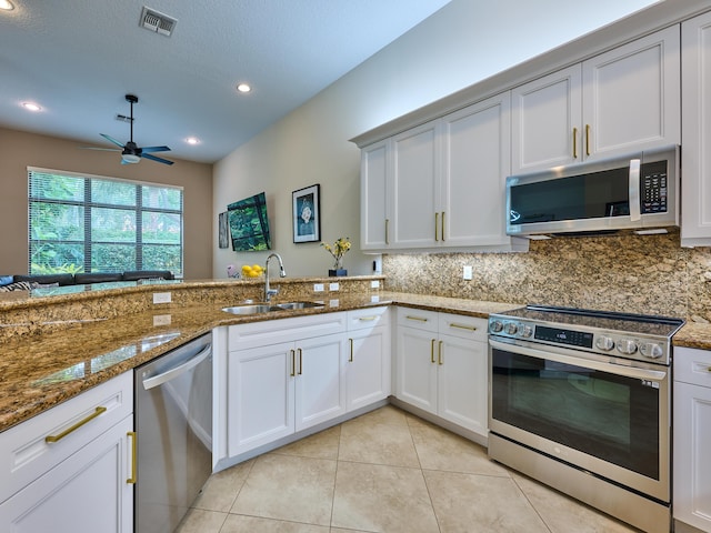 kitchen featuring white cabinetry, appliances with stainless steel finishes, decorative backsplash, dark stone countertops, and sink