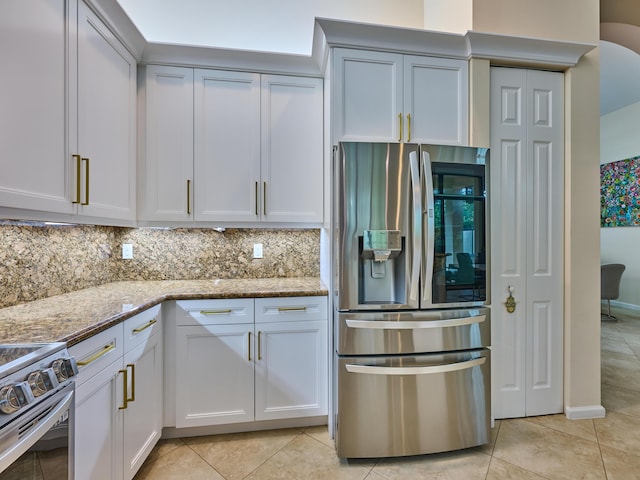 kitchen featuring light tile patterned floors, white cabinetry, stainless steel appliances, tasteful backsplash, and light stone counters