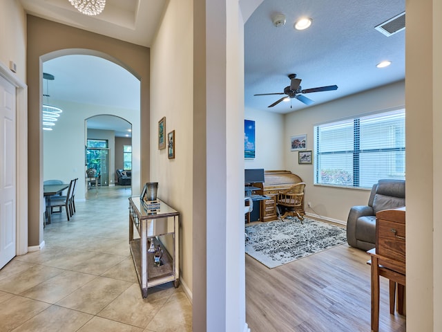 hall featuring light tile patterned floors and a textured ceiling